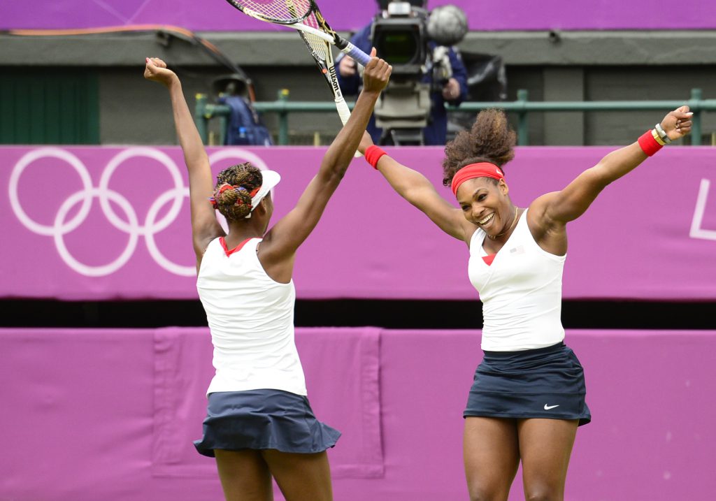 US Venus Williams (L) and Serena Williams celebrate after winning the women's doubles gold medal match of the London 2012 Olympic Games by defeating Czech Republic's Andrea Hlavackova and Lucie Hradecka, at the All England Tennis Club in Wimbledon, southwest London, on August 5, 2012. AFP PHOTO / LEON NEAL (Photo credit should read LEON NEAL/AFP/GettyImages)